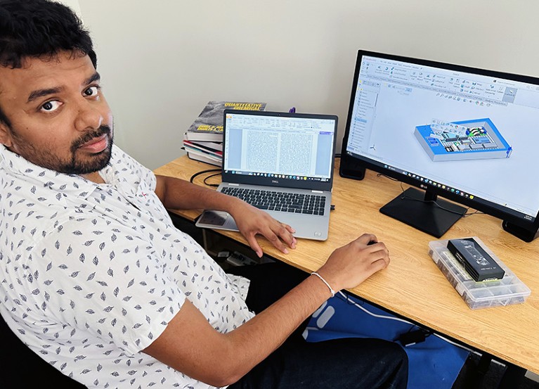 Nuwan Bandara working on his computer, with reference books on the desk.