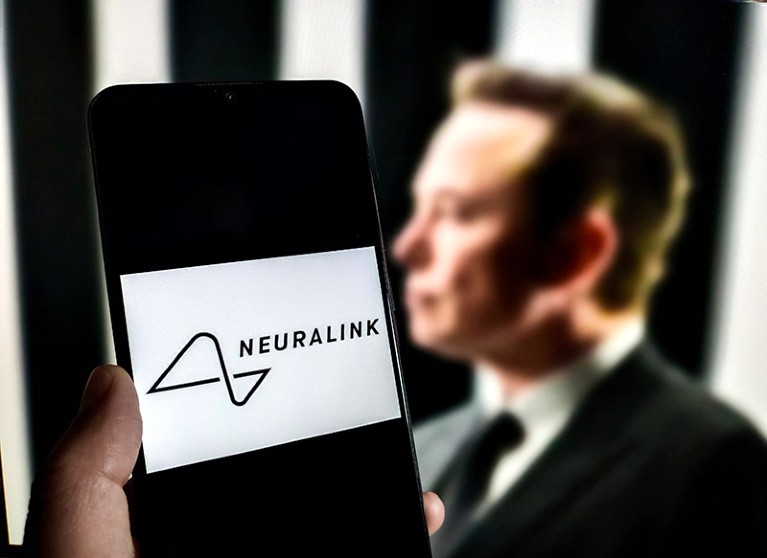 The logo for Neuralink on a smartphone screen in front of a portrait of Elon Musk.
