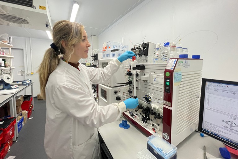 Alice Francis working in the lab while wearing a white lab coat and blue gloves