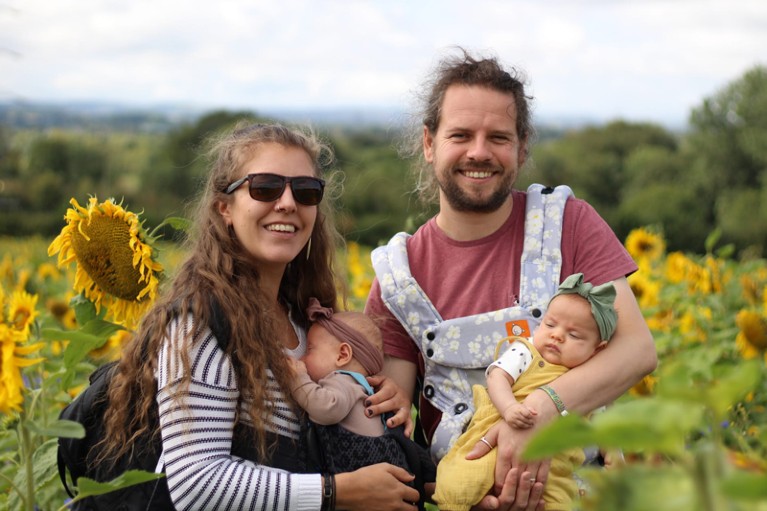 Gemma Fisher poses for a portrait with her husband and two baby daughters in a sunflower field