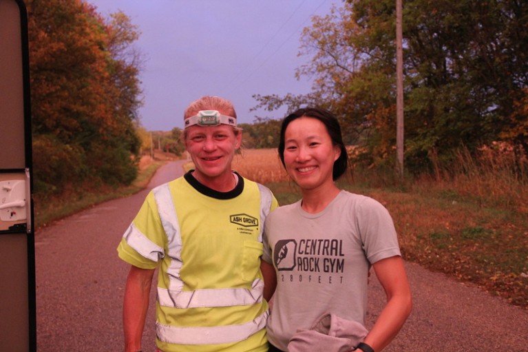 Jenny, wearing a hi-vis top and a head torch, poses with Yanting Teng, a graduate student in physics at Harvard