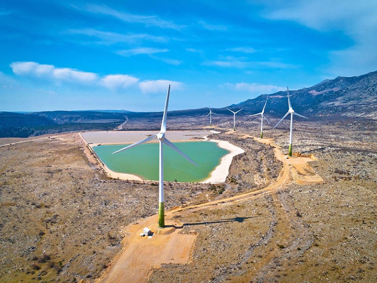 Wind power turbines under Velebit mountain view, Alkaline pool from abandoned factory, Dalmatia region of Croatia.