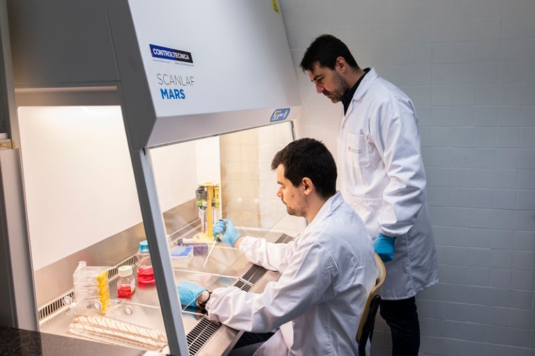 Albert Manzano and Joan Montero work at a fume hood on a microfluidic device used to predict cancer therapy response