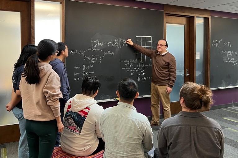 George Karniadakis explains fractional calculus to his students and postdocs at a blackboard