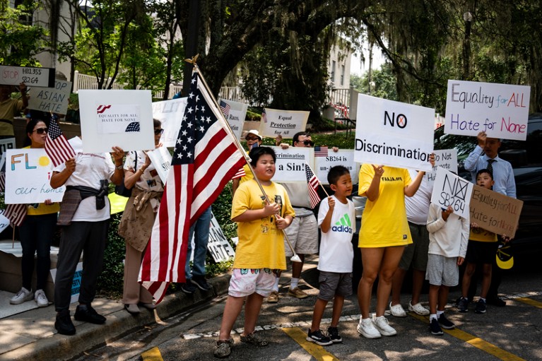 Adults and children hold the US flag and signs calling for equality during a demonstration.