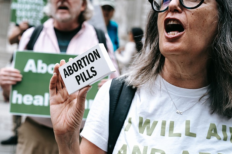 A protester holds up a box labeled "abortion pills" at a rally