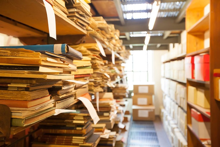 Old documents and books stored on shelves in a library's archive.