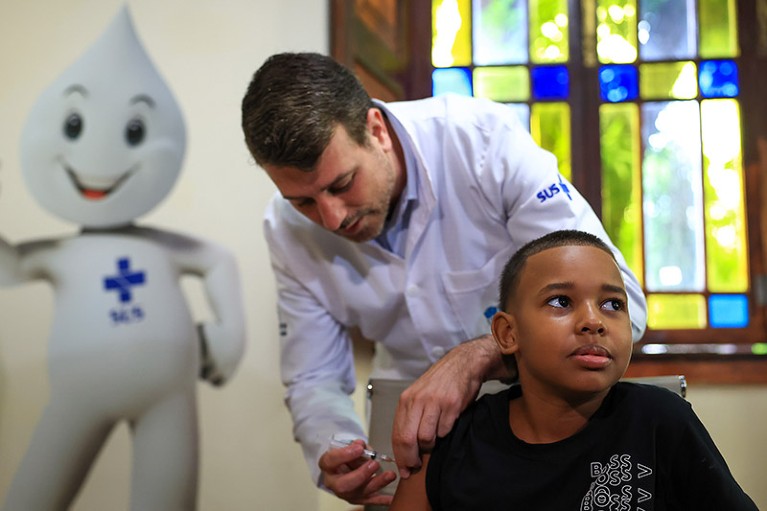 Rio de Janeiro's Health Secretary Daniel Soranz applies a dose of the Qdenga dengue vaccine to a young recipient.