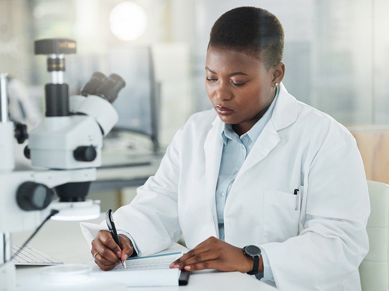 Shot of a young female scientist writing notes while working in a lab.