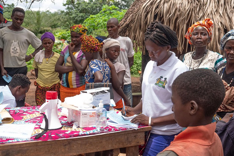 Vaccination team member Baison Salone (left) facilitates a vaccination clinic in Kafugumbah village, Karene district.
