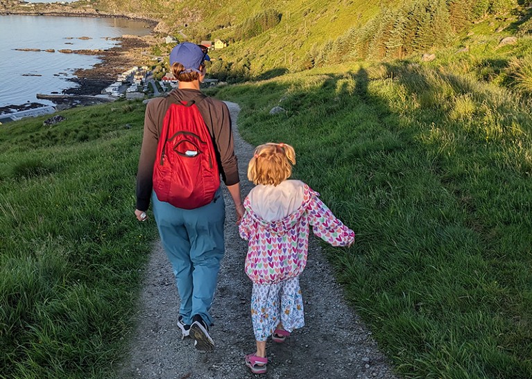 Lindsey Smith Taillie and daughter walking seaside near hills while spotting puffins in Runde, Norway, June 2023
