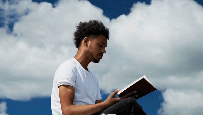 An animated sequence from a video generated by OpenAI's Sora of a young man reading a book while sitting on a cloud.