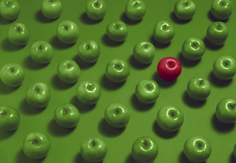 One red apple surrounded by multiple green apples on a green background.