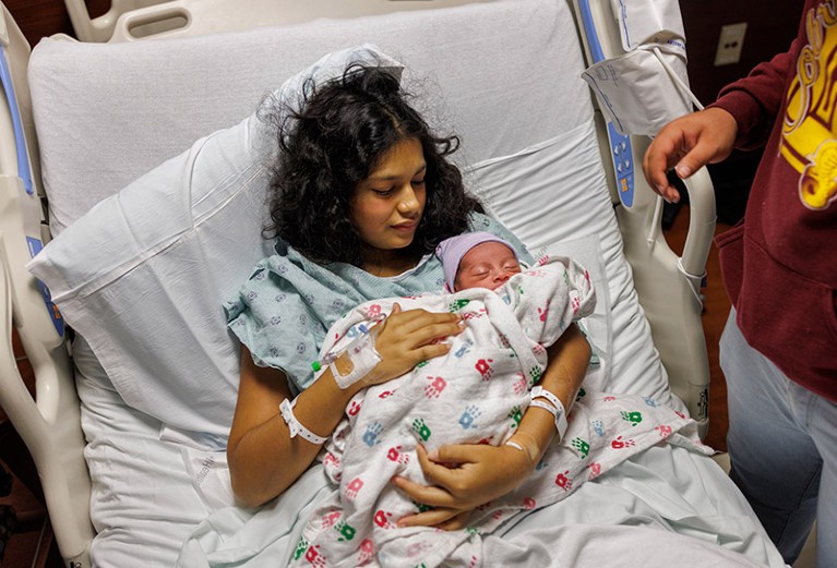 A young woman holds her newborn baby in a hospital bed at at the University of Chicago Medical Center.