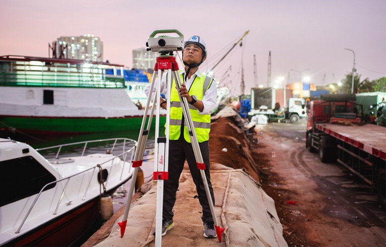 Muh Aris Marfai measures the ground level compared to level zero of the sea (average sea level) using a geodetic digital level, at a tide gauge station at the Sunda Kelapa port of Jakarta, Indonesia.