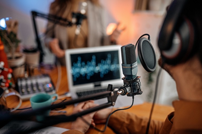 Two people with a microphone in the foreground, recording a podcast during an interview in a studio.