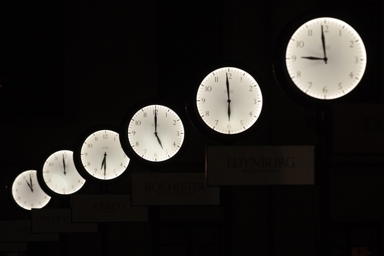 A row of six clocks showing different times at night