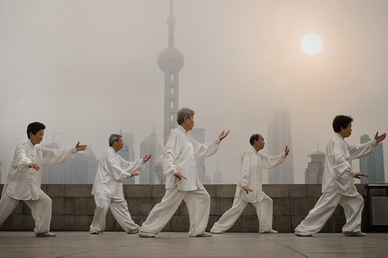 A group of people doing tai chi outdoors with the Shanghai city skyline in the background.