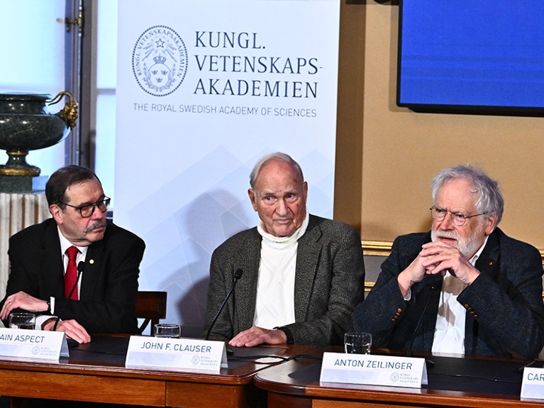 Alain Aspect, John Clauser and Anton Zeilinger seated at a press conference.
