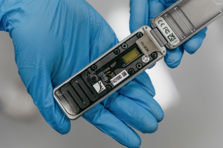 Two gloves hands holding a MinION portable and real time device for DNA and RNA sequencing