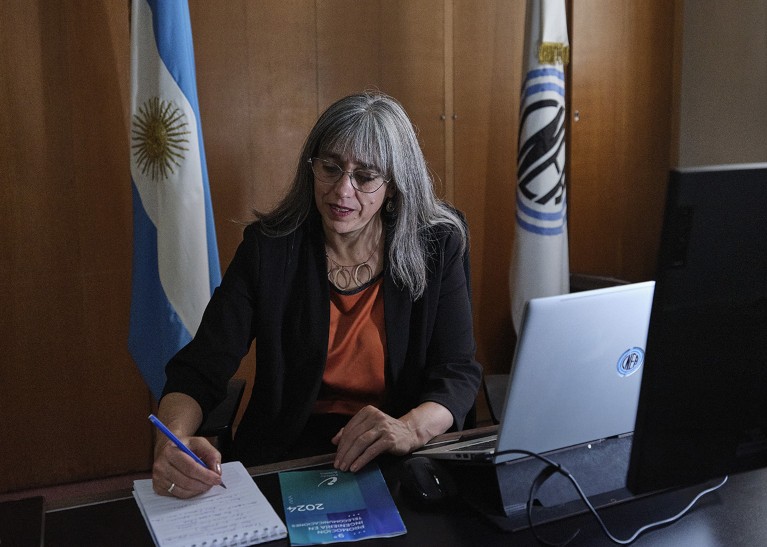 Portrait of Adriana Serquis at her desk, taking notes in front of a computer.