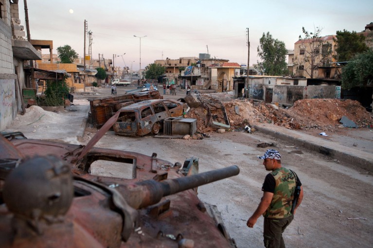 A man walks past a destroyed Syrian forces tank in northern Aleppo