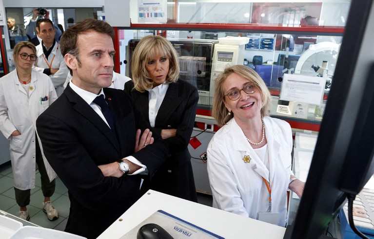 Emmanuel y Brigitte Macron escuchan a una científica mostrarles su investigación en una pantalla de su laboratorio del Institut Curie.