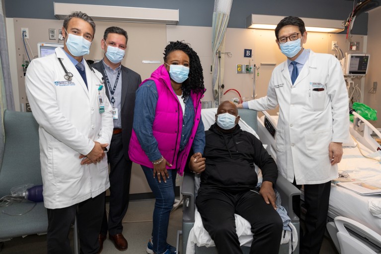 Five people wearing face masks pose in a hospital.