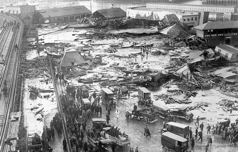 Black and white photo of the collapsed tank full of molasses that flooded Boston on January 15th, 1919.