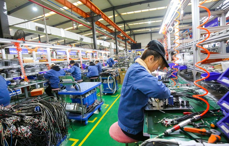 Femal worker in the foreground works among others on a production line at the world's largest supplier of transformers. Rugao, Jiangsu Province, China.