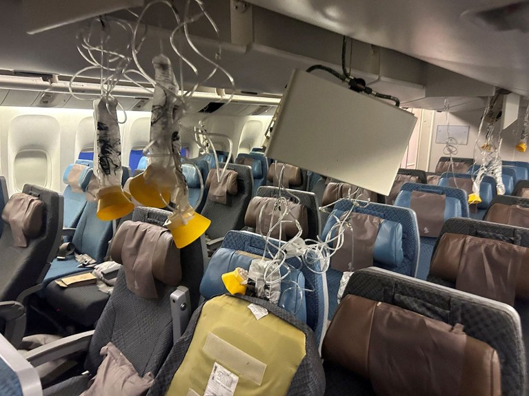 Emergency masks hang from the ceiling of the chaotic interior of Singapore Airline flight SQ32.1