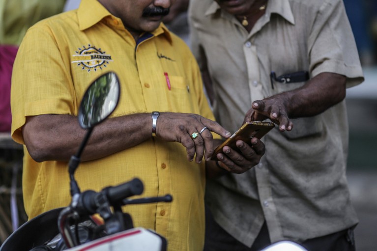 Close-up of two men using a smartphone in Mumbai, India