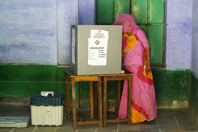 Una mujer no identificada vestida con ropa de color rosa vota en un colegio electoral