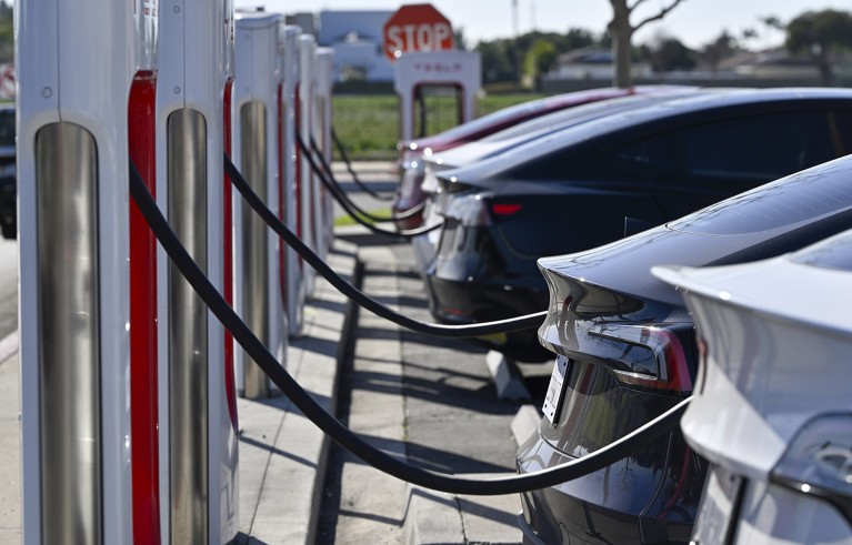 Five different coloured Tesla electric cars plugged in to charge at an outdoor charging station in California.