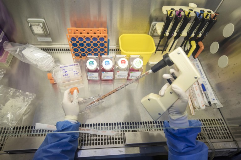 Close-up of a technician wearing gloves transferring product into a bottle inside a fume hood