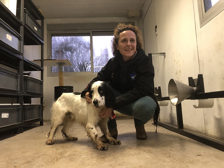 Woman crouches down to the right of a white and black dog