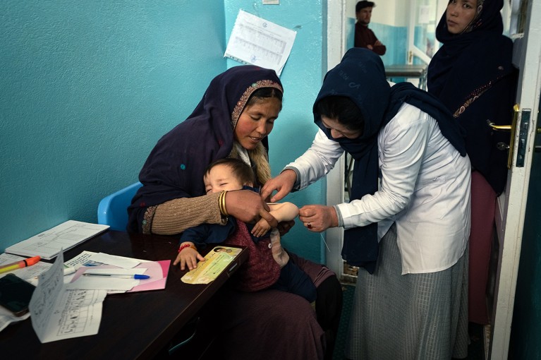 A nurse cares for a child in its mother's arms at a clinic in the Foladi Valley near Bamian city, Afghanistan.
