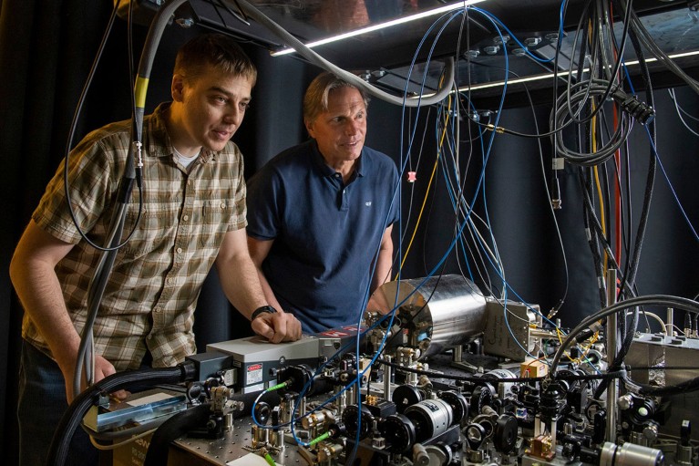 物理学家 Jason Hogan 和 Mark Kasevich 在他们正在开发的用于测量引力波的设备旁拍照。