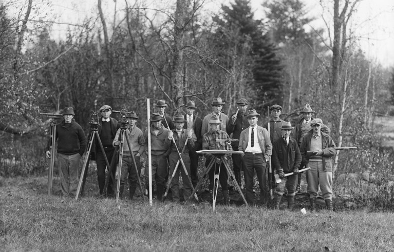 Surveyors stand with tools in Maine.