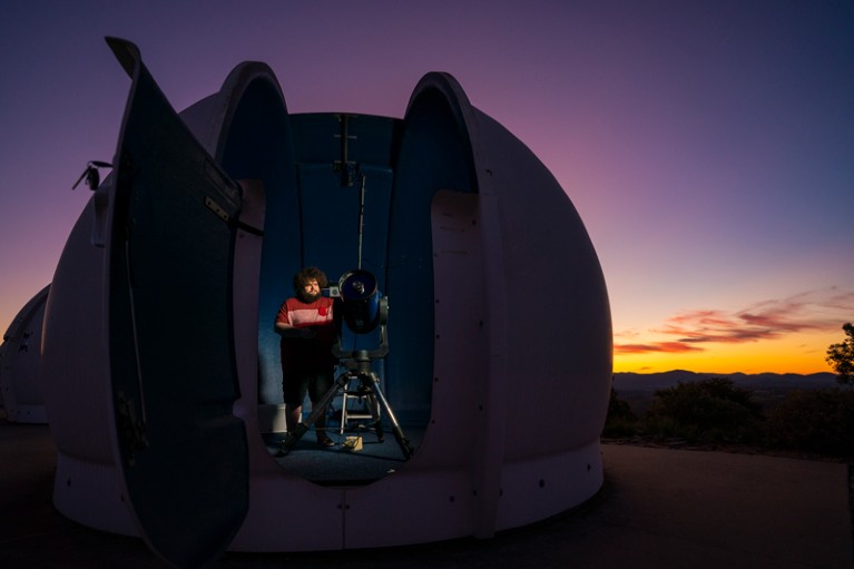 Peter Swanton preparing a telescope in an observatory dome at dusk