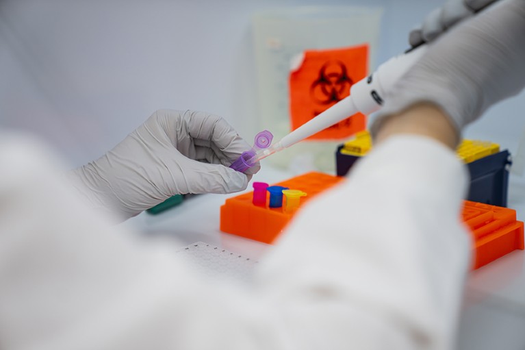 Closeup view of a pipette inserting fluid into a purple test tube