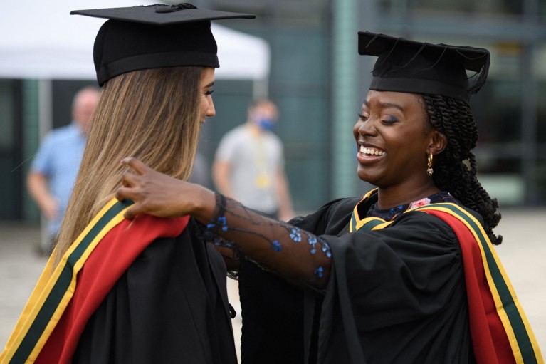 Close-up of two female students smiling at their university graduation ceremony