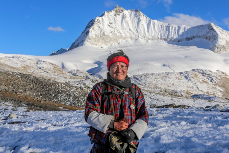 Dechen Dorji posing for a photo infron of a snow-covered peak in the High Himalayan mountains
