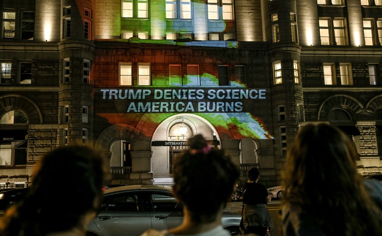 Activists project flames and commentary on the side of the Trump International Hotel to protest President Donald Trump's response to science and climate change, 2020.