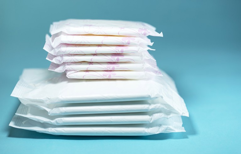 A neat pile of sanitary pads and absorbent sheets pictured against a blue background.