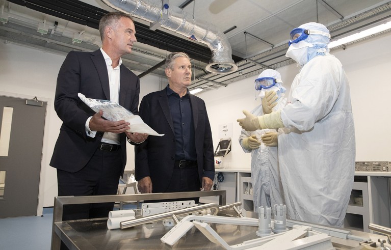 Sir Keir Starmer y Peter Kyle (izquierda) hablan con dos empleados de AstraZeneca que usan equipo de protección mientras visitan el laboratorio de AstraZeneca en Macclefield en 2023.