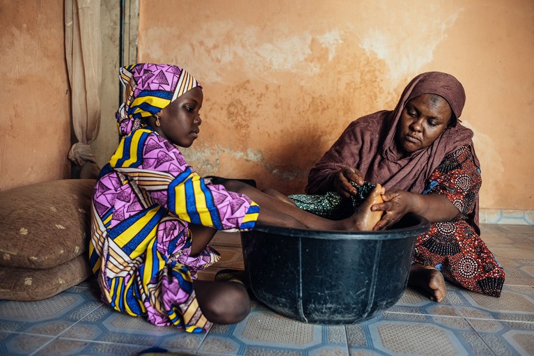 A mother uses warm water to massage the legs of her daughter, who has sickle cell disease, in Kano, Nigeria.