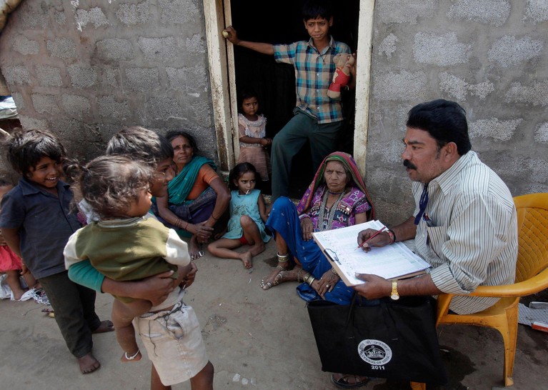 A 2011 census worker notes down details from a crowd of women and children in a slum area in Hyderabad, India.