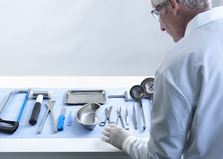 A male Pathologist preparing tools for an autopsy