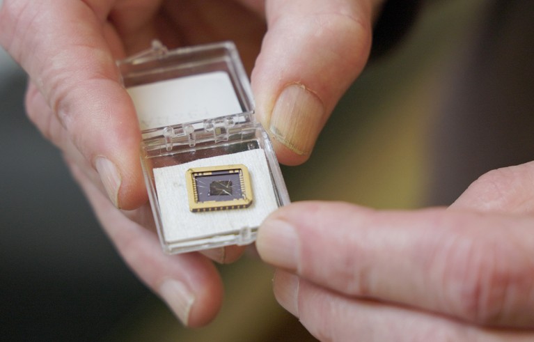 Close of a researchers hands holding a graphene device grown on a silicon carbide substrate chip.